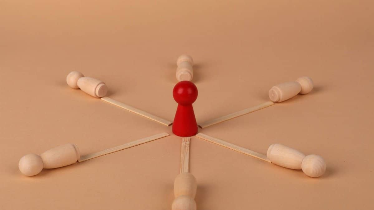 Red leader figure connected to wooden figures, emphasizing leadership and teamwork.