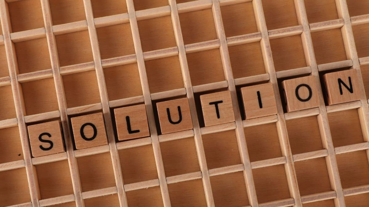 Word tiles spelling 'solution' on a wooden grid background for business concept.