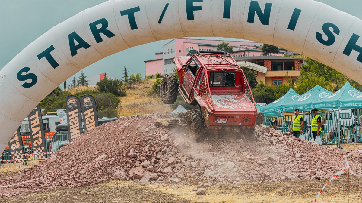 Red off-road vehicle races over rocky terrain, highlighting an adrenaline-filled outdoor event.