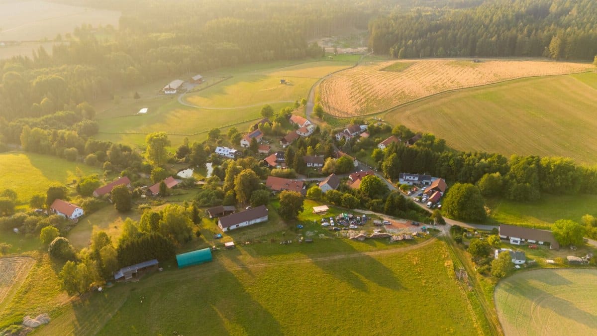 Scenic aerial view of a rural village surrounded by fields and forests in summer.