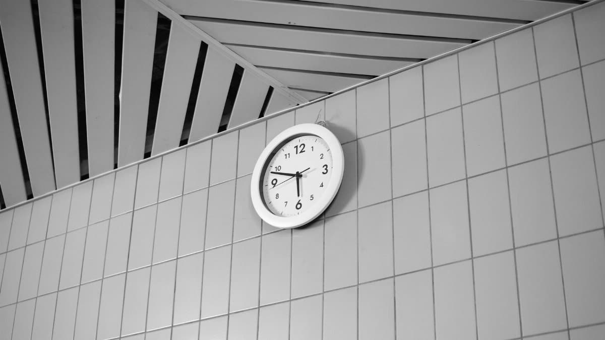 A black and white wall clock displays time on a tiled wall, creating a modern aesthetic.