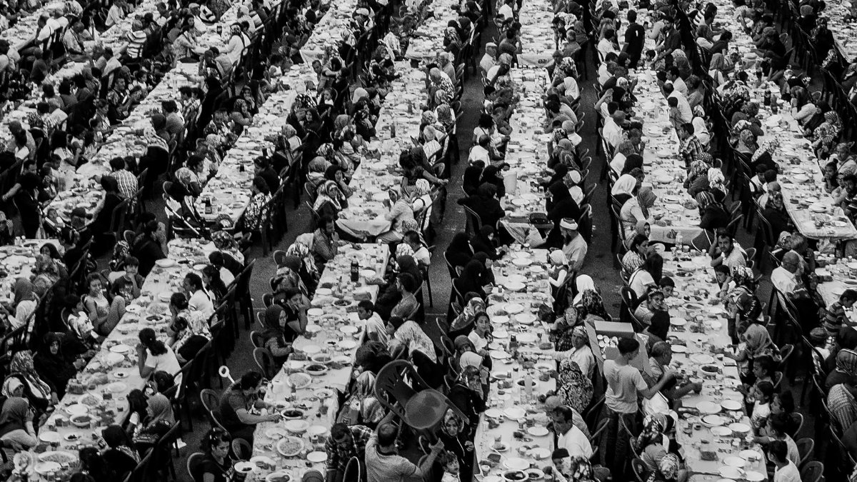 Black and white aerial view of a large outdoor banquet with numerous tables and people.