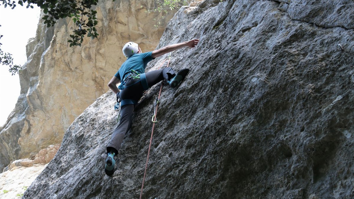 A determined rock climber scaling a cliff face in Entrechaux, France showcasing courage and strength.