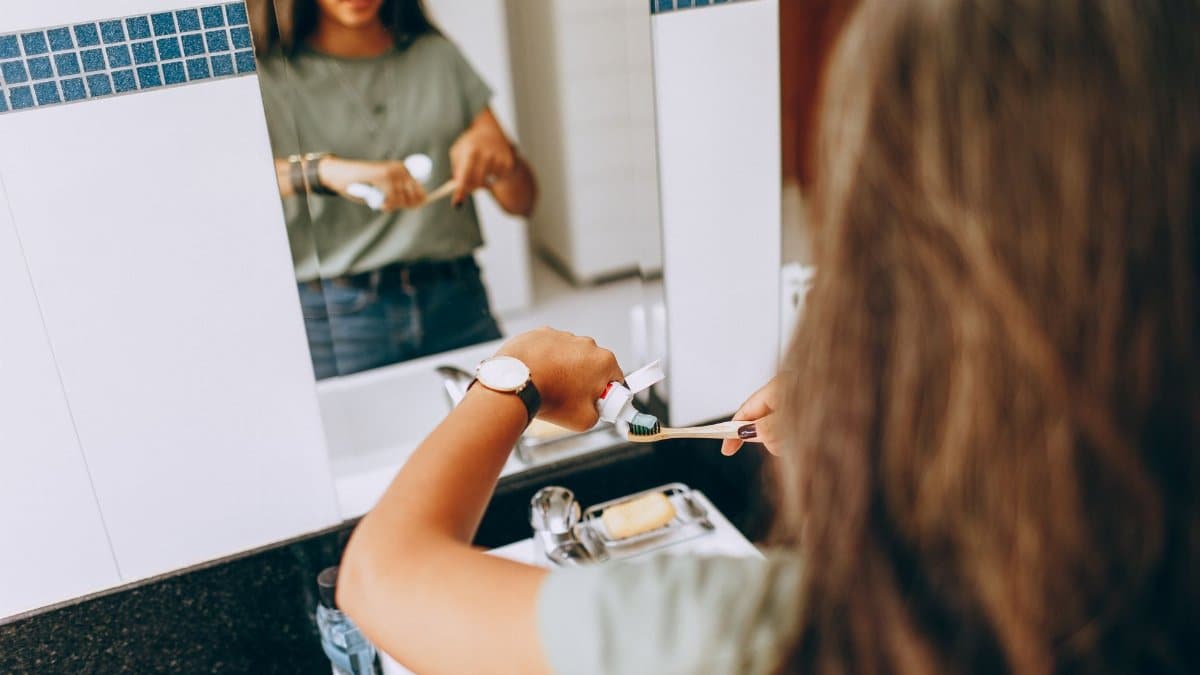 Teen girl brushing teeth in a modern bathroom, emphasizing daily hygiene routine.