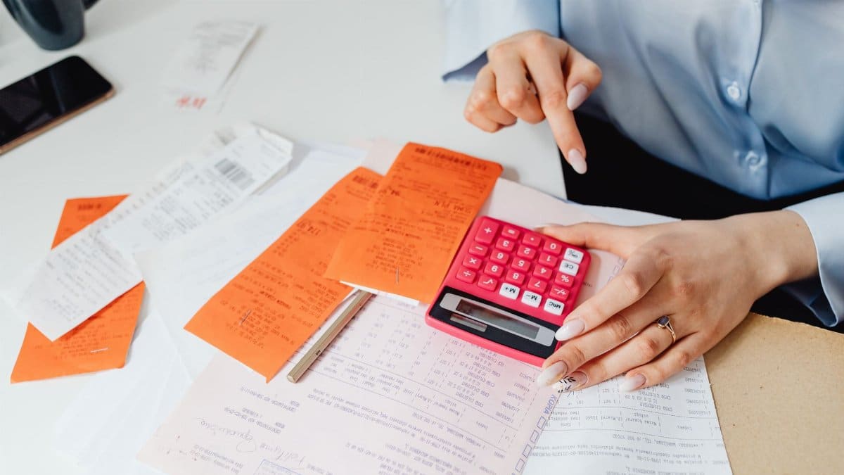 Businesswoman calculates expenses using receipts and calculator at desk. Ideal for finance, accounting themes.