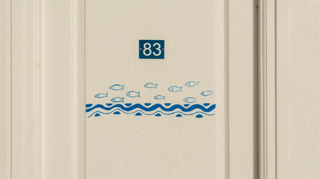 Minimalist door with number 83 and fish pattern design, ideal for nautical themes.