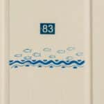 Minimalist door with number 83 and fish pattern design, ideal for nautical themes.