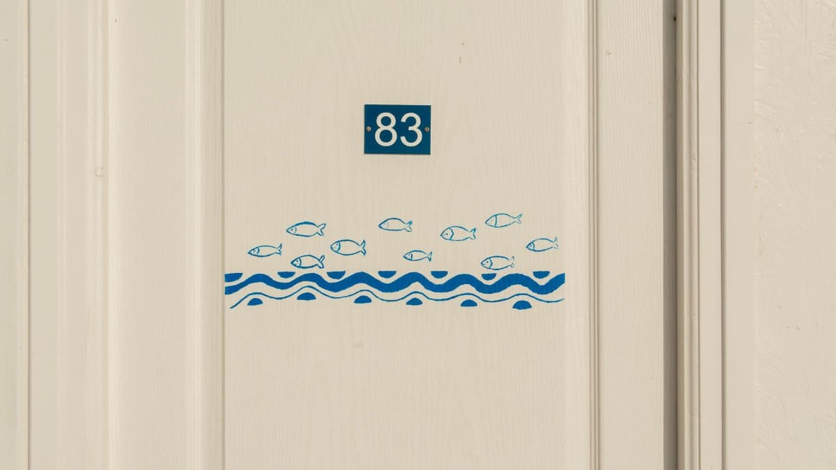 Minimalist door with number 83 and fish pattern design, ideal for nautical themes.