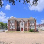 Front view of a vintage brick building under a clear blue sky in Houston, Texas.