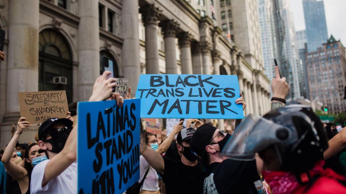 A vibrant city protest advocating for Black Trans rights with diverse participants holding signs.
