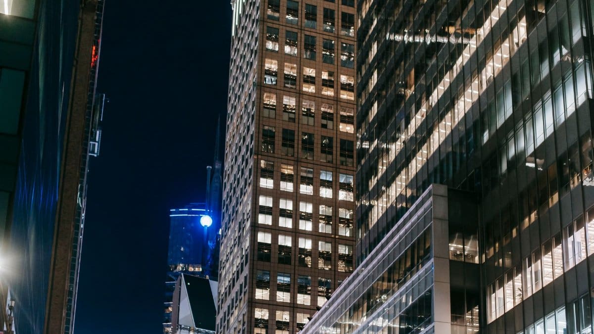 From below of high rise towers with lights in windows located in business city district at night