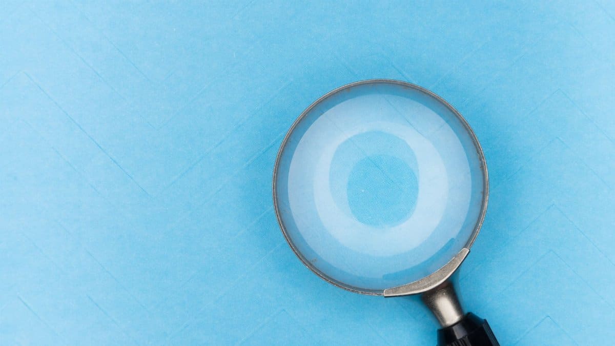 Close-up of a magnifying glass on a blue background, focusing on detail and clarity.