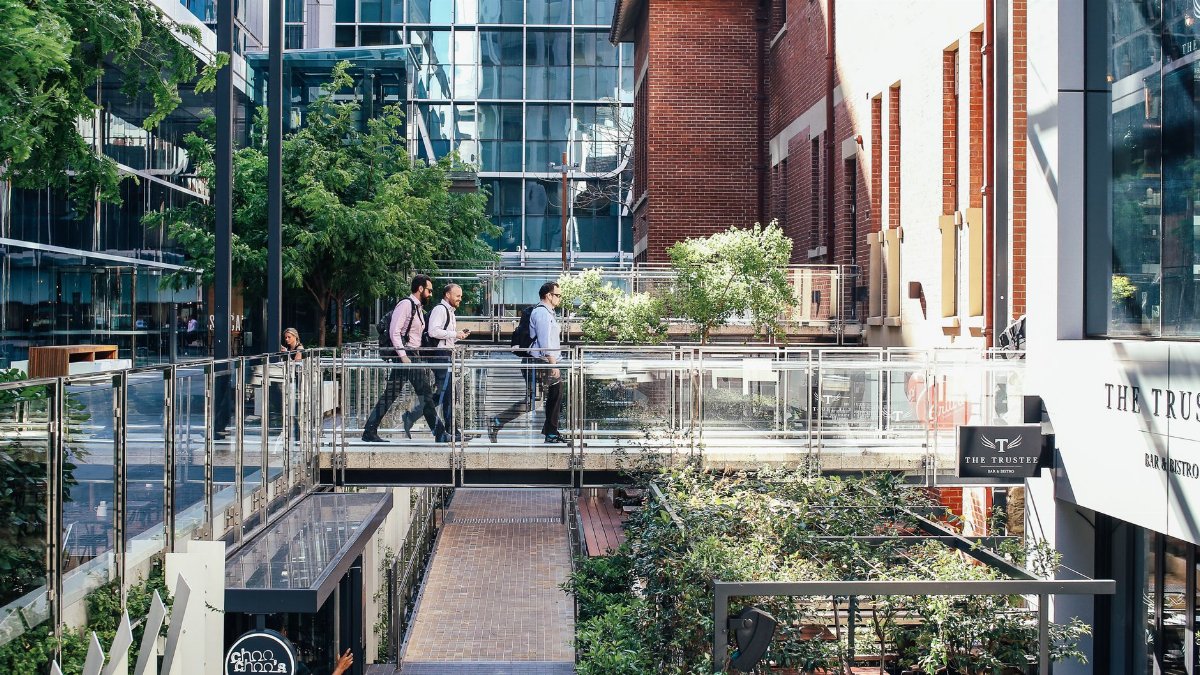 Office workers walking in a modern urban district with glass and brick buildings.