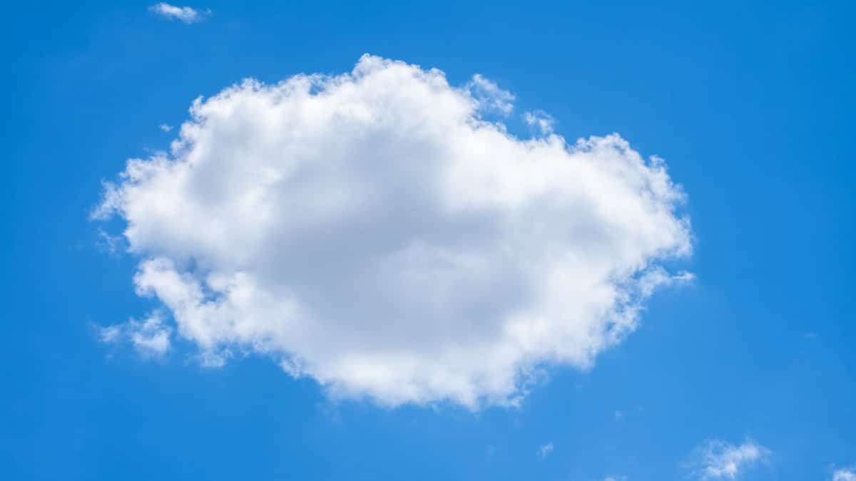 A single fluffy white cloud against a vibrant blue sky on a clear summer day.
