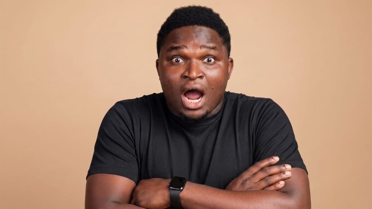 A shocked man in a black shirt with an open mouth and crossed arms.