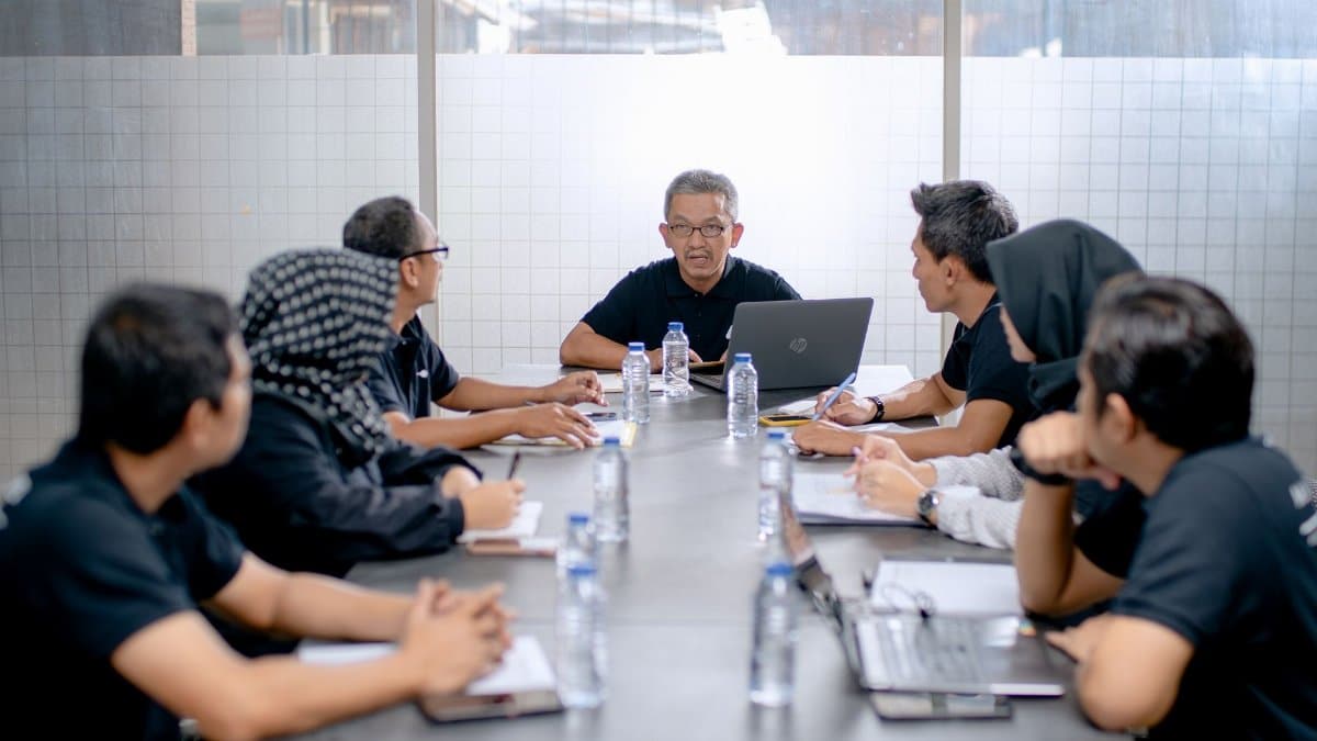 Professional team meeting around a conference table in an office setting.
