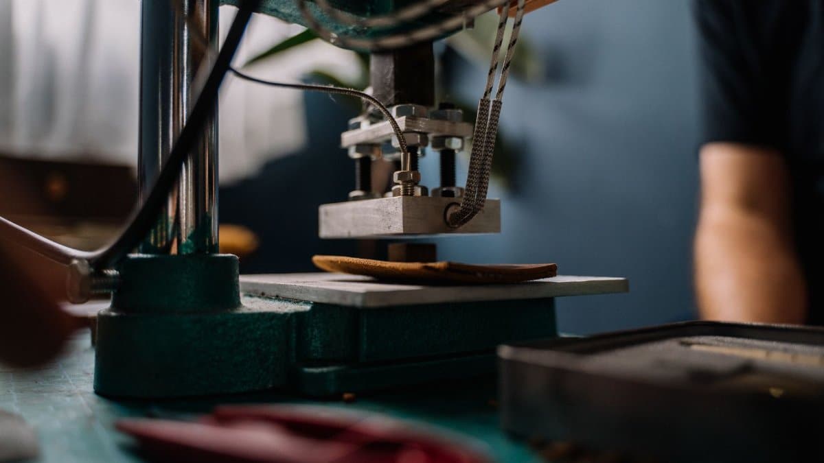 Detailed view of a leather press machine in use, crafting in a workshop setting.