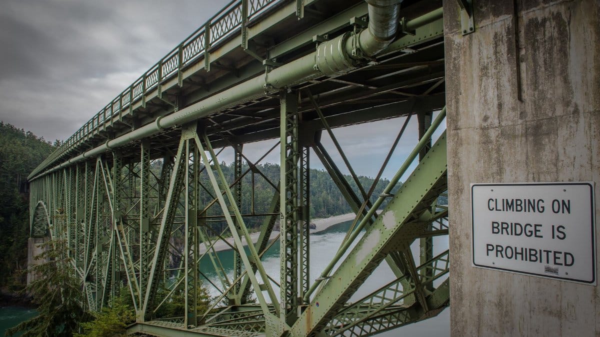 Explore the green steel bridge in Vancouver, BC with scenic river views and a prohibition sign.