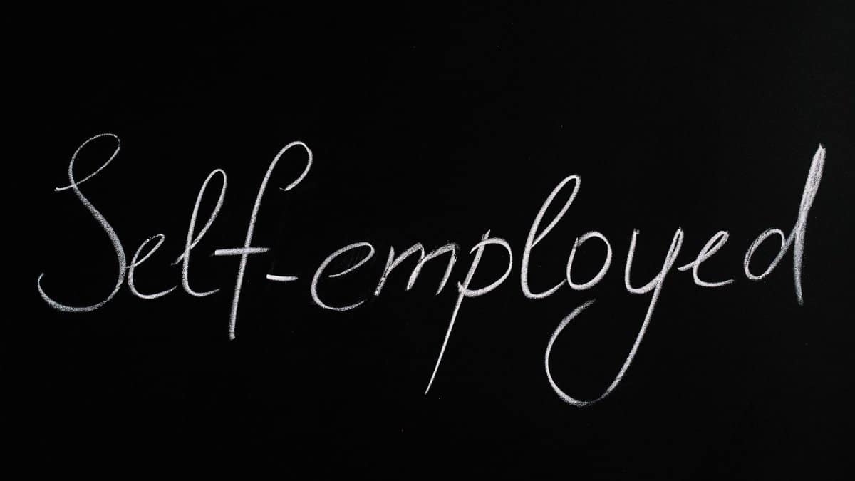 Handwritten 'Self-employed' in chalk on a blackboard background for business concepts.