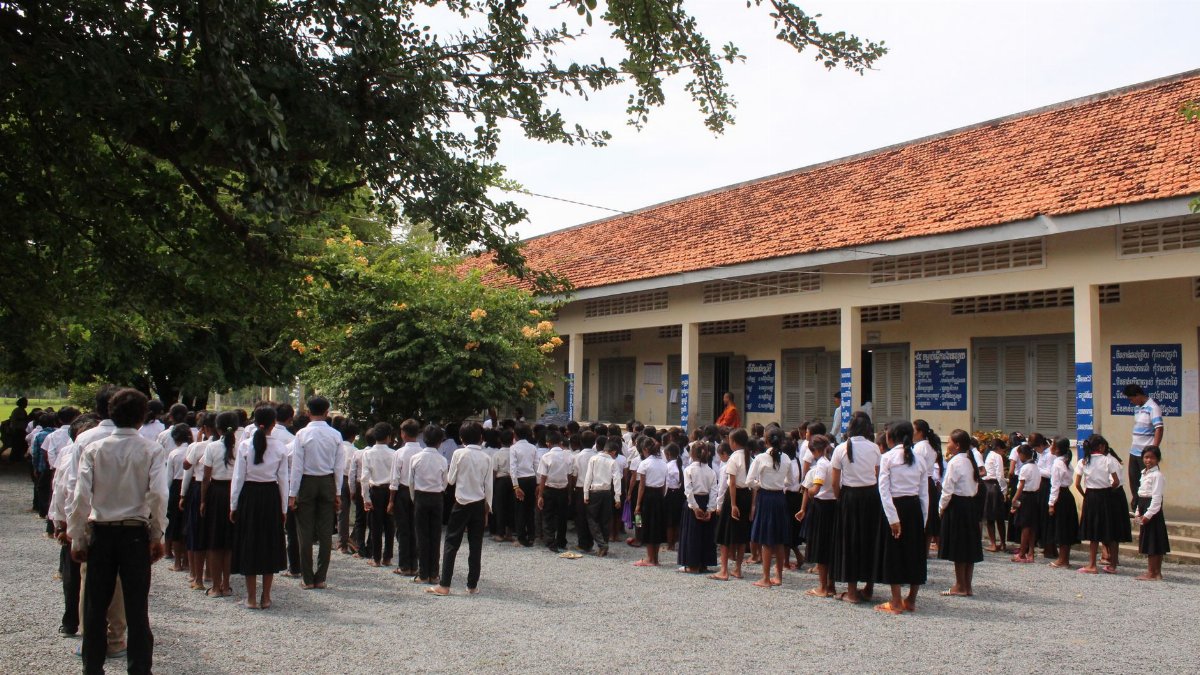 Students gather for a school assembly outside in Cambodia, fostering a sense of community.
