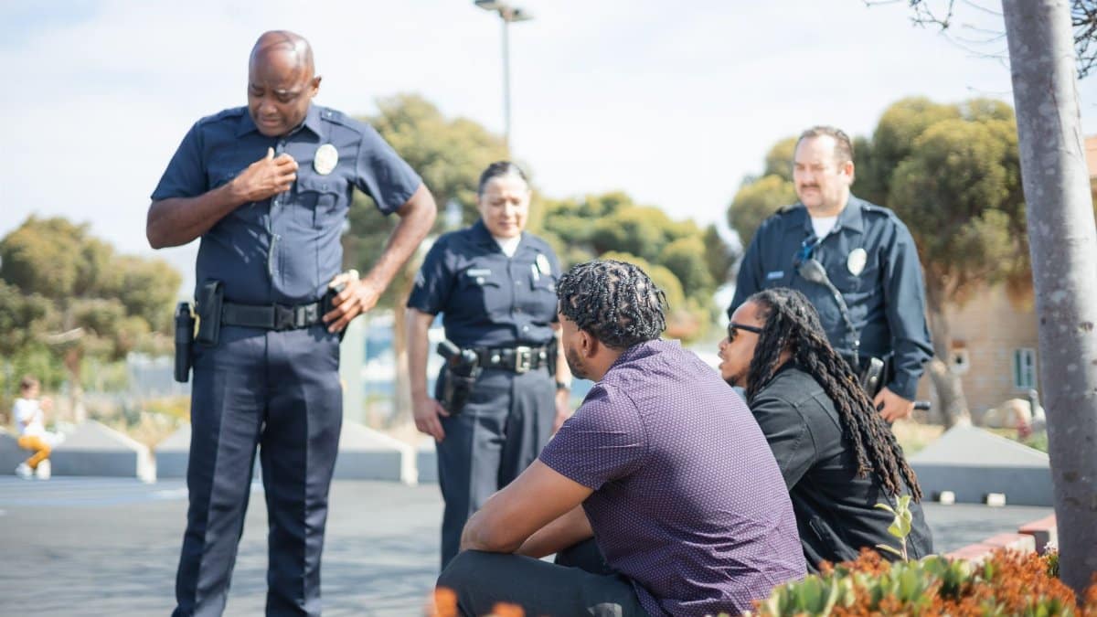 Police officers interacting with individuals on the street in a diverse setting, showcasing community engagement.