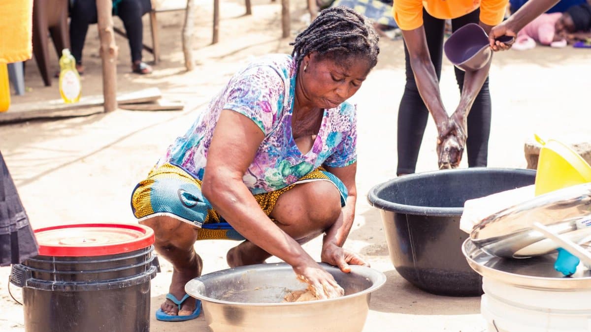 Women working together in an outdoor community setting with bowls and containers.