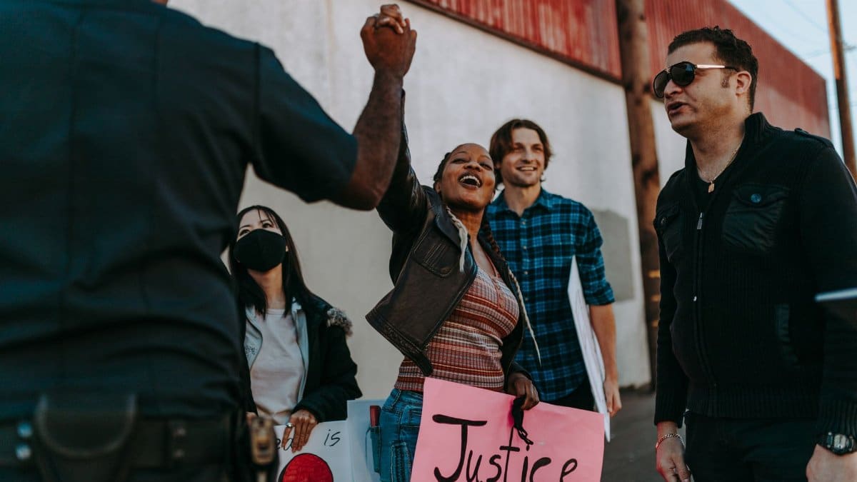 A diverse group rallies with signs at a peaceful protest outdoors. Positive interaction with police enhances community spirit.