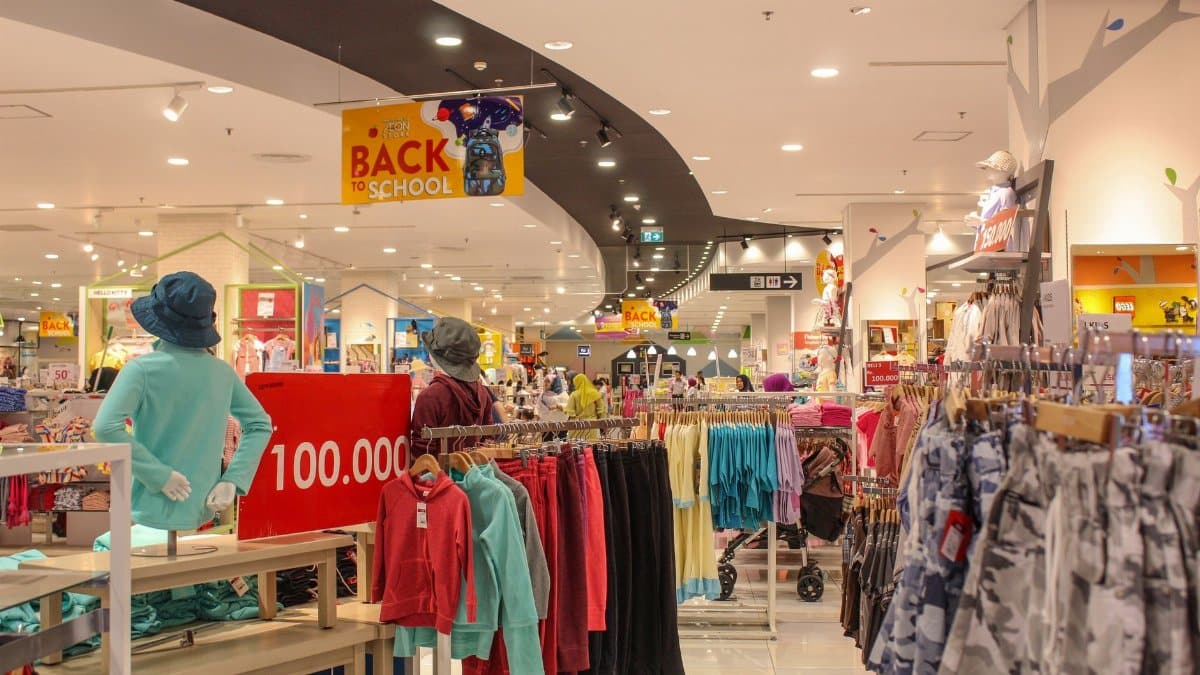 Lively department store aisle displaying colorful back to school clothes under bright lighting.
