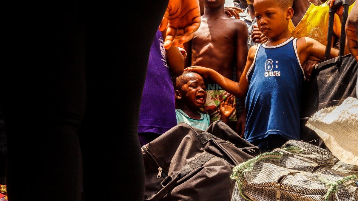 A group of children gather for community service, displaying diverse emotions outdoors.