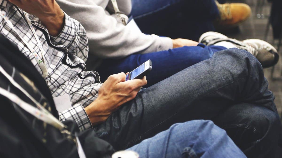 People sitting at a conference casually checking smartphones, communicating and networking.