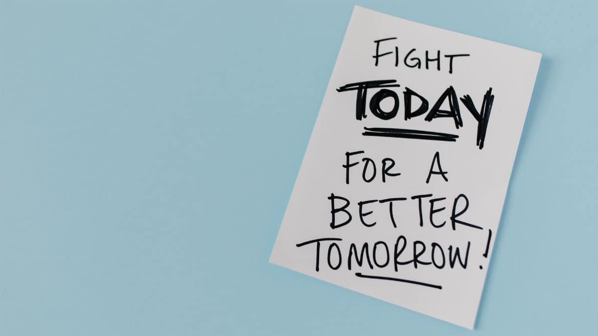 Inspirational handwritten message urging action for a better future on paper over a blue backdrop.