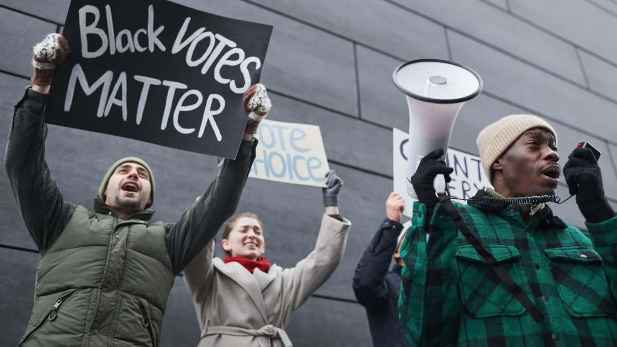A multicultural group of protesters advocating for voting rights holding placards outdoors, emphasizing diversity and democracy.