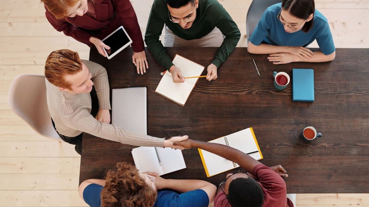 Top view of a diverse business team meeting with a handshake across the table. Collaborative working environment.