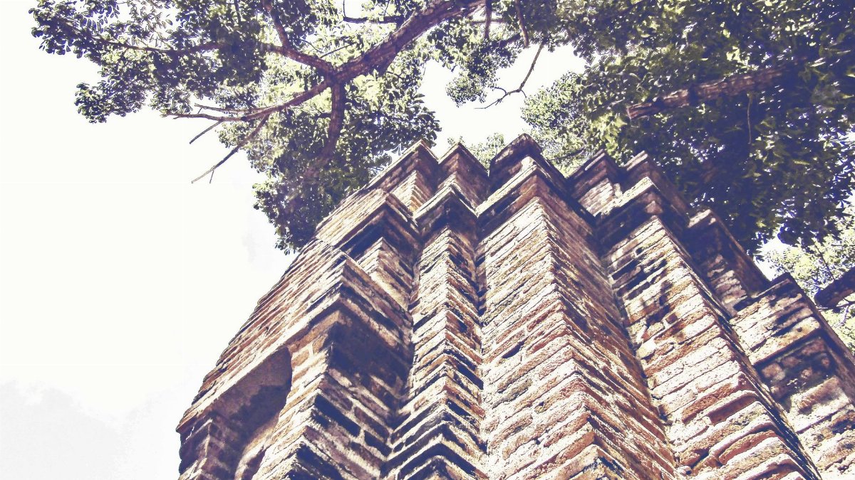 A striking low angle shot of ancient brick architecture with trees in the background.