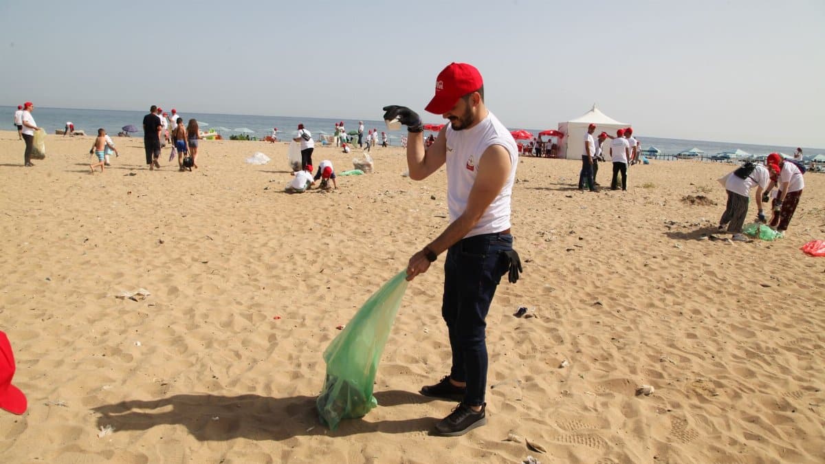 Volunteers cleaning up beach in Algiers, promoting environmental awareness.
