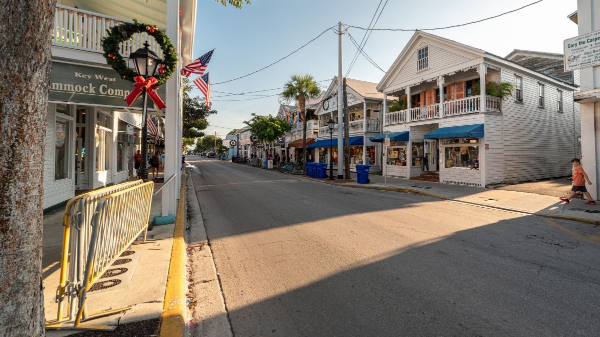 Sunny Key West street scene with American flags and holiday wreaths, capturing the festive charm of the area.