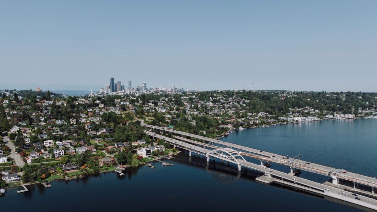 Scenic aerial shot of Seattle skyline with bridge spanning across a lake on a clear day.