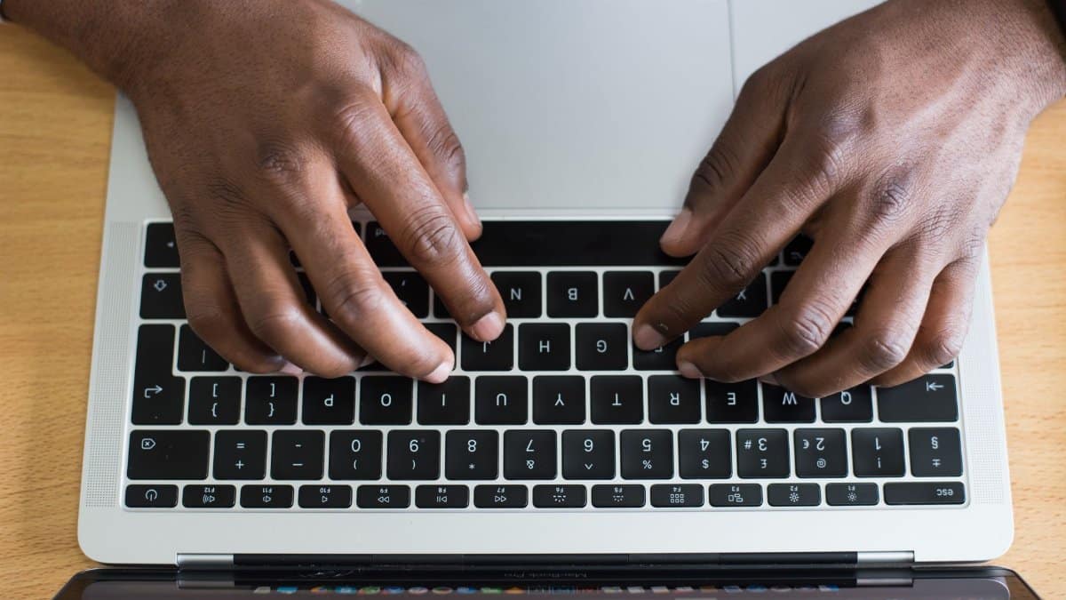 Hands typing on a laptop keyboard, showcasing modern technology in an indoor workspace.