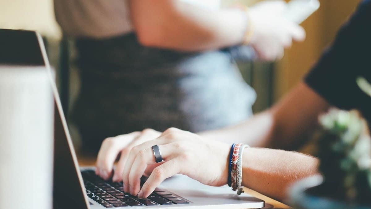 Close-up of hands typing on a laptop with a blurred background.