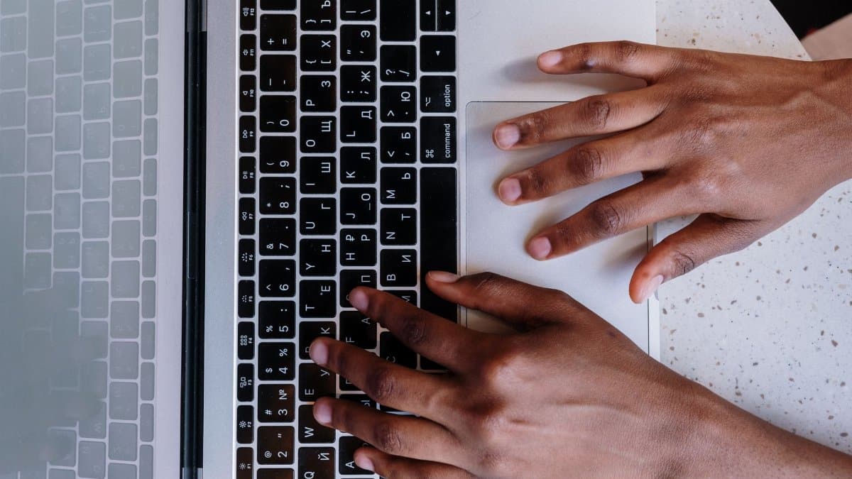 Hands typing on a laptop keyboard, showcasing online work and technology.