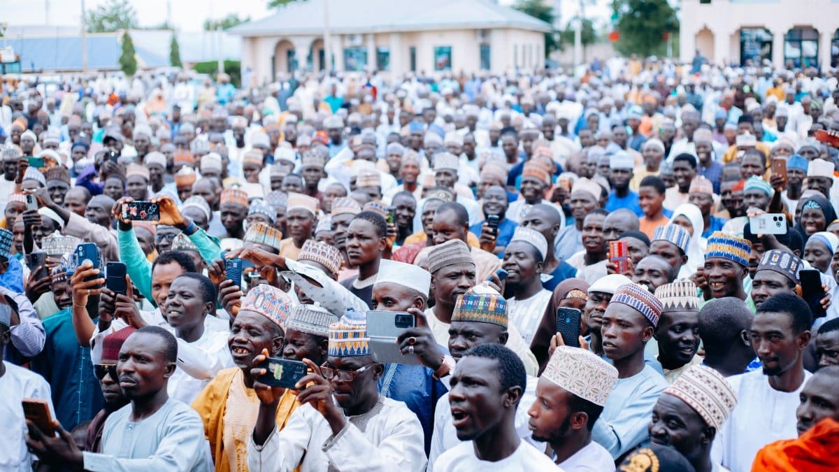 A vibrant outdoor crowd capturing moments with smartphones at a large public gathering.