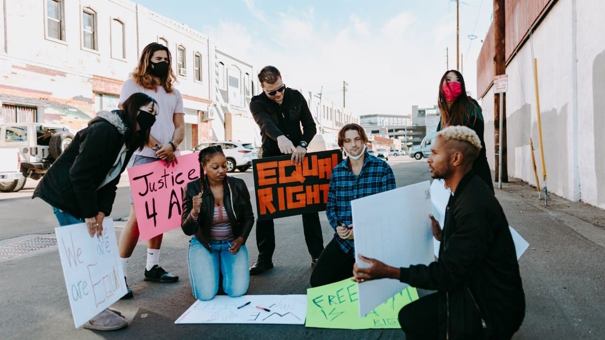 A diverse group of protesters advocating for equal rights using placards outdoors.