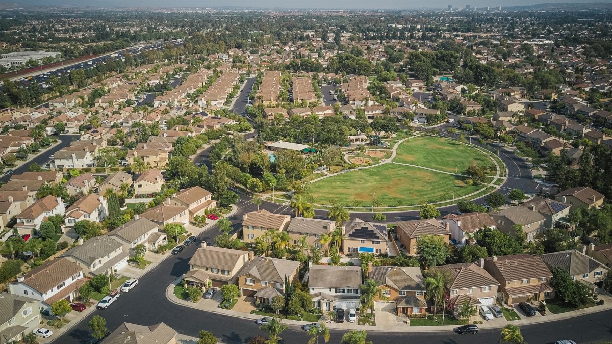 Drone shot of a spacious suburban neighborhood featuring a central park with numerous houses.