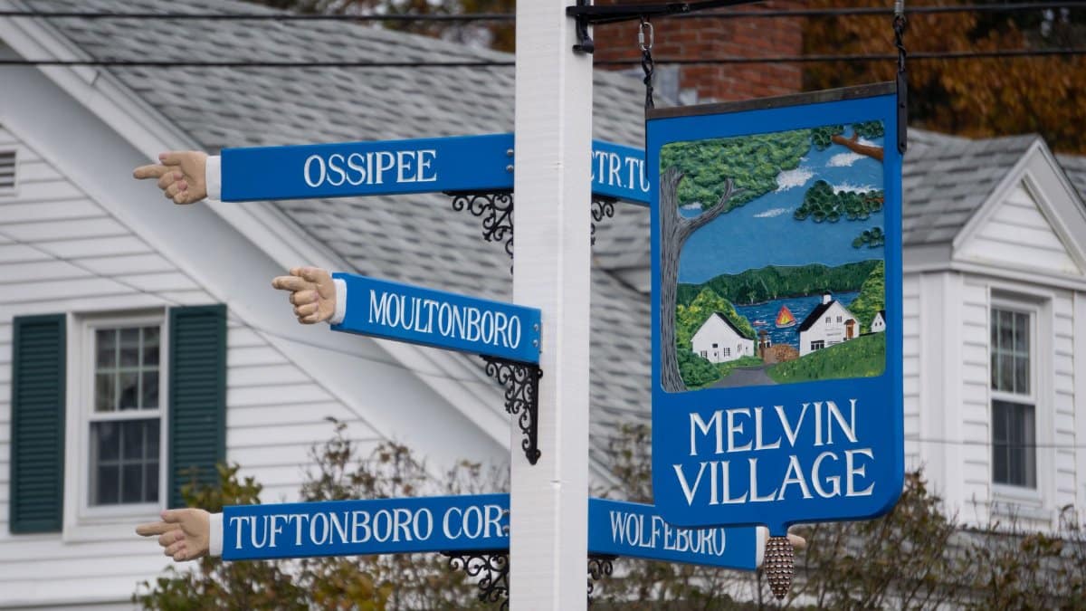 Colorful directional sign pointing to various locations in rural Melvin Village, NH.