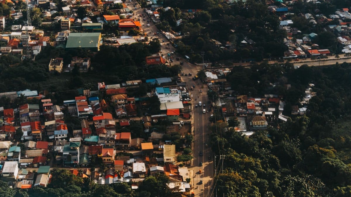 Aerial shot of a bustling urban area with vibrant rooftops and greenery, showcasing intricate road networks.