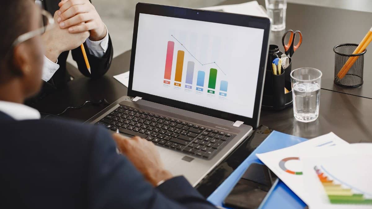 Two professionals analyzing a business graph on a laptop during a meeting.