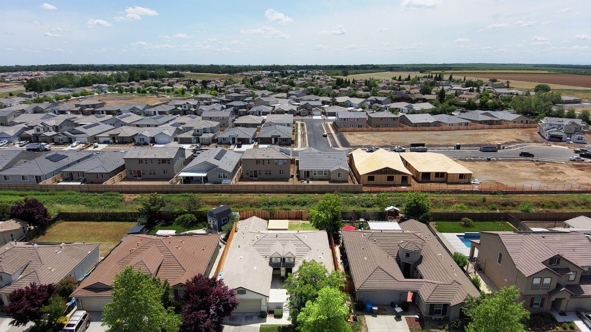 Drone view of suburban neighborhood with new housing developments and green surroundings.