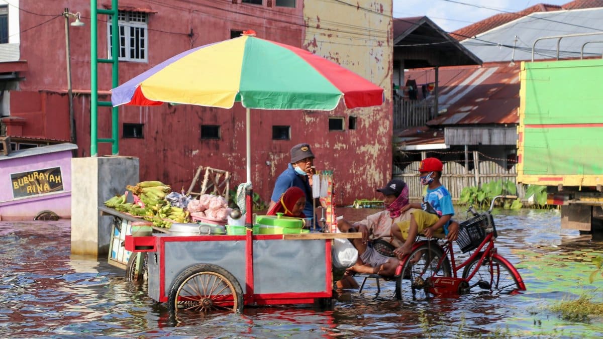 A vibrant street food cart in a flooded street in Kalimantan Selatan, Indonesia, showcasing local resilience.