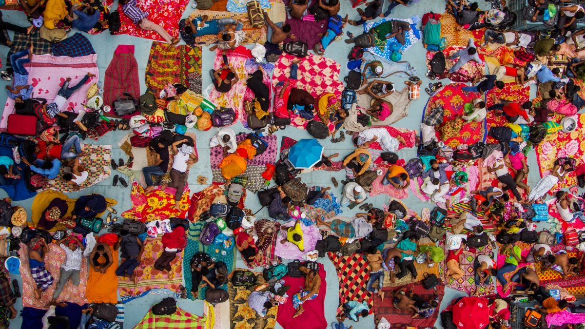Aerial view of a diverse group of people on colorful blankets outdoors, showcasing vibrant textiles and community spirit.