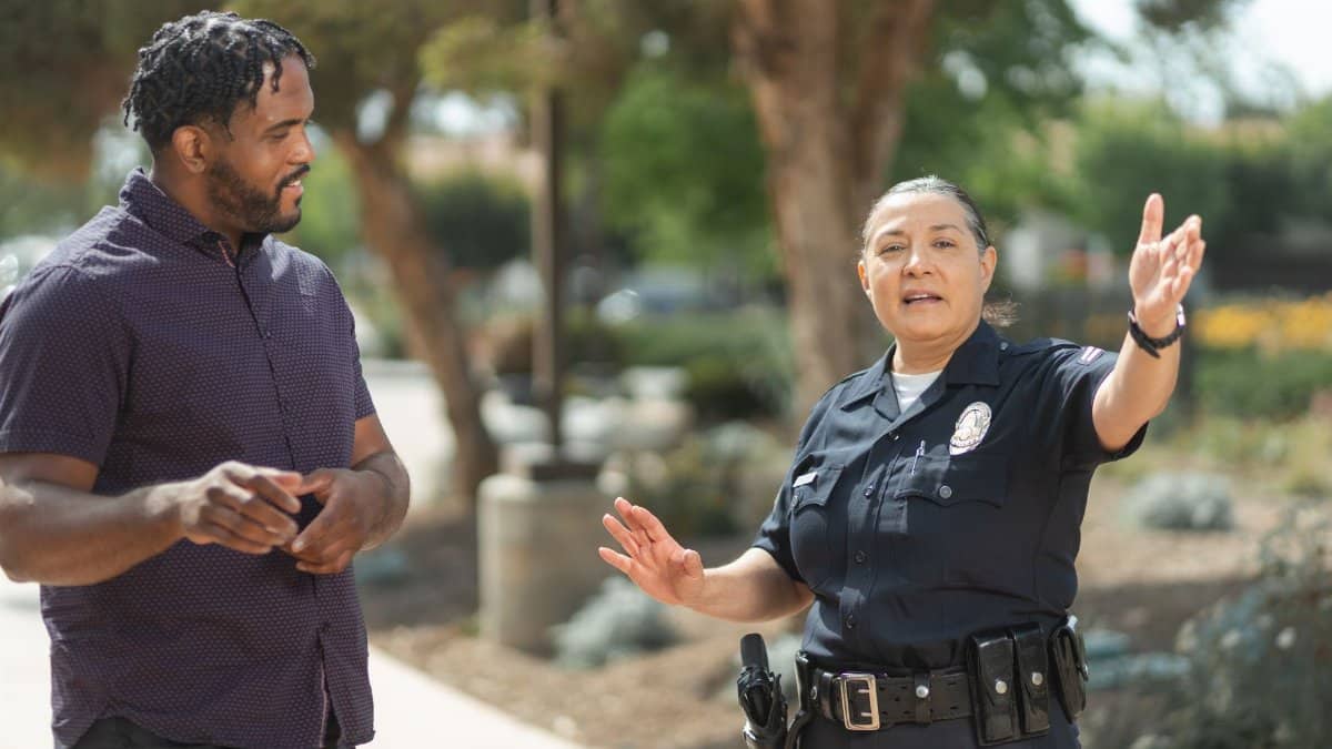 Police officer in uniform engaging in a conversation with a man on a sunny day, promoting community relations.